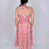 Tara Dress in pink ditsy floral print with red contrast piping, halter V neckline, fitted bodice, and full gathered midi skirt
