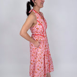 Tara Dress in pink ditsy floral print with red contrast piping, halter V neckline, fitted bodice, and full gathered midi skirt