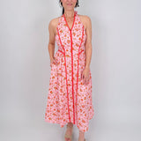 Tara Dress in pink ditsy floral print with red contrast piping, halter V neckline, fitted bodice, and full gathered midi skirt
