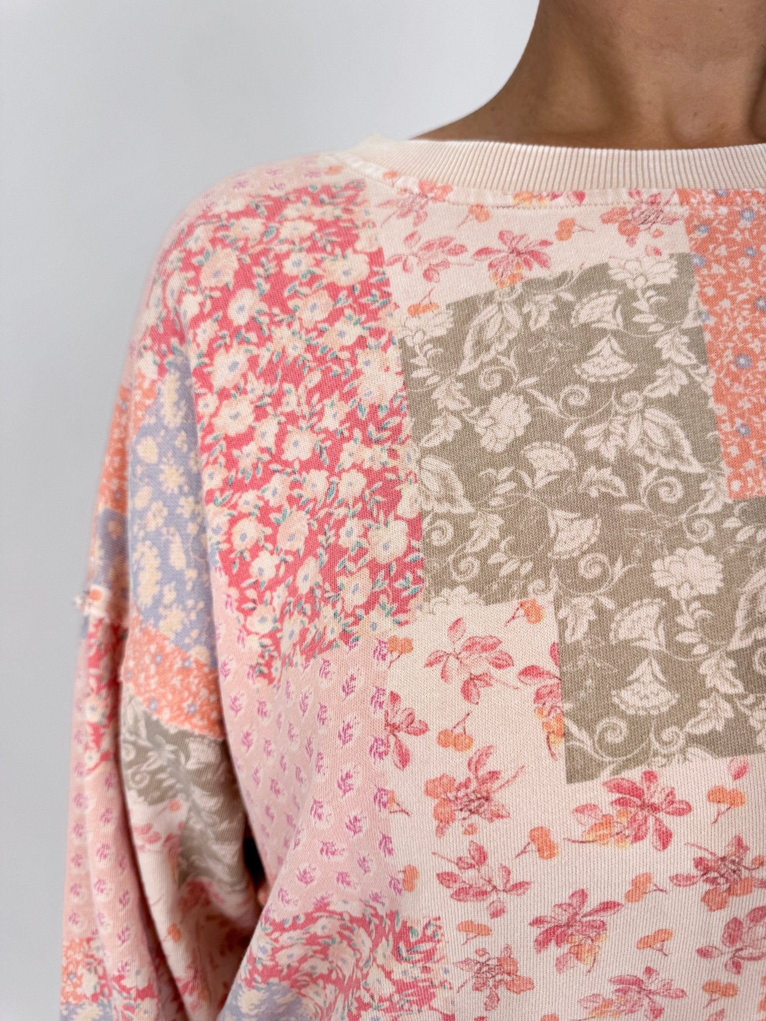 Take A Risk Patchwork Top in floral patchwork print with pink, peach, periwinkle, and olive tones with crew neckline and ribbed trim